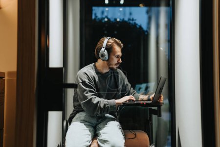 Männliche Person mit Video-Meeting-Anruf auf seinem Laptop an Telefonzelle im Büro.
