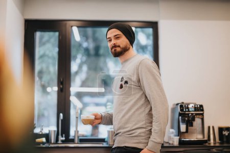 Employé masculin tenant une tasse de café ayant une conversation avec ses coéquipiers pendant la pause au travail.