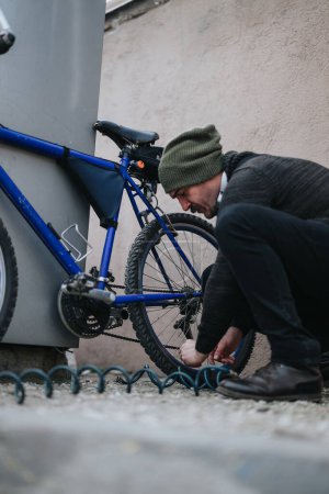 Individuo enfocado cerrando su bicicleta con una cadena en las calles de la ciudad por seguridad y antirrobo.