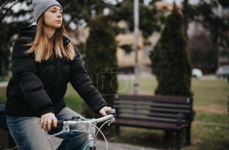 Lässige Frau auf dem Fahrrad in einem Stadtpark während der Wintersaison.