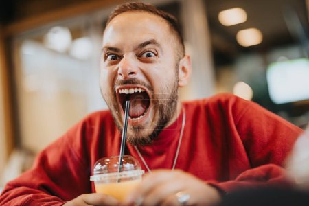 Persona masculina con reacción a gritos después de tomar un sorbo de un cóctel muy caliente y picante.