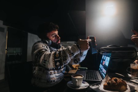 Concentration intense en tant que professionnel créatif édite la vidéo sur un ordinateur portable dans une pièce faiblement éclairée, traduisant dévouement et passion pour son métier.