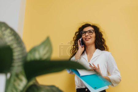 Lovely, curly haired, female employee analyzes reports, does paperwork, and engages in creative problem-solving to drive profitability and growth.