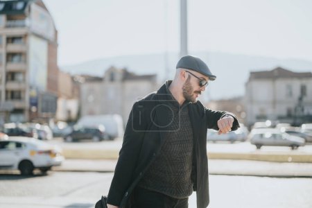 Stylish businessman walking and checking time on wristwatch in sunny urban environment.
