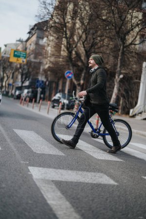 Hombre joven con atuendo casual camina con su bicicleta en un cruce de cebra en un entorno urbano, mostrando un estilo de vida activo y transporte ecológico.