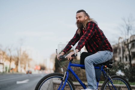 A bearded businessman on a blue bicycle pauses in an urban setting, embodying eco-friendly commuting and flexible work.