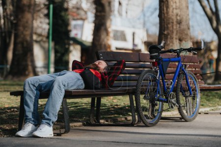 Empresario disfrutando de un momento tranquilo en el parque urbano, descansando en un banco con su bicicleta a su lado.
