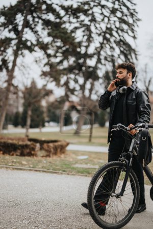 Homme d'affaires élégant vérifiant son téléphone tout en se tenant debout avec un vélo à l'extérieur, mettant en valeur un mode de vie actif et équilibre de travail.