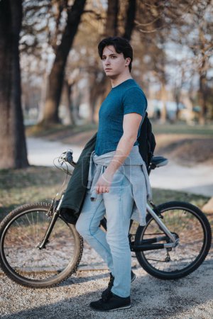 Casual young man with bicycle in a serene park setting, enjoying a day out in nature away from the busy urban life