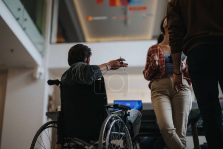 Un usuario de silla de ruedas participa activamente en un debate en equipo de trabajo, destacando la inclusión y la accesibilidad en el lugar de trabajo.
