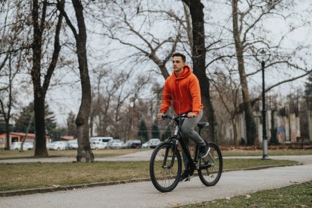 Active young adult enjoying a bike ride in a scenic park on an overcast day, embracing the outdoors.
