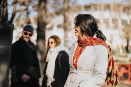 Stylish woman smiling on sunny city street with blurry people in background.