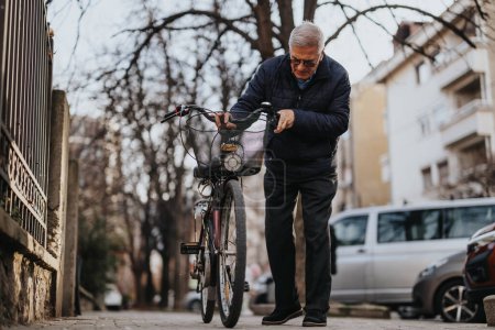 Hombre mayor revisando bicicleta en una calle urbana tranquila en otoño.