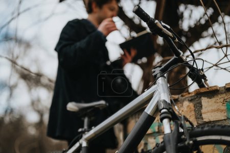 Un joven empresario con una bicicleta, comprometido en el trabajo a distancia fuera, encarnando un estilo de vida laboral moderno.