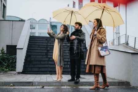 Eine Gruppe von Freunden oder Kollegen kauert sich an einem regnerischen Tag unter leuchtend gelben Regenschirmen und zeigt urbanen Lebensstil und Wetterbereitschaft.