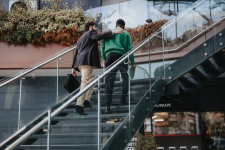Lässiger Outdoor-Moment zweier Männer im Gespräch, gemeinsam Treppen hinauf, um Freundschaft und urbanen Lebensstil zu demonstrieren.