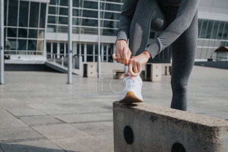 Primer plano de una atleta atándose las zapatillas antes de correr por la ciudad, centrándose en su rutina de fitness.