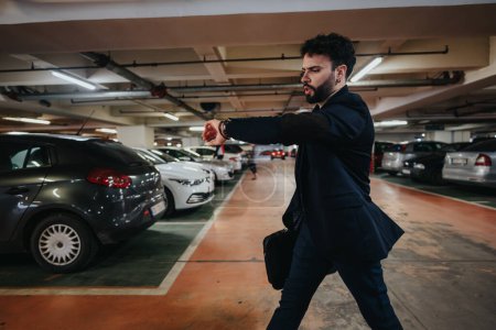 Busy businessman in suit hurrying through a car park, looking at his watch and running late for a meeting.