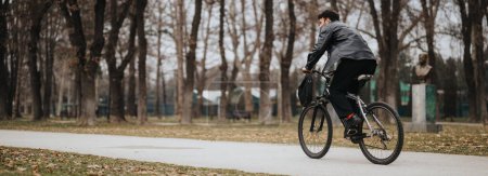 Stylish businessman enjoys the flexibility of working outdoors on his bicycle in a scenic urban park setting.
