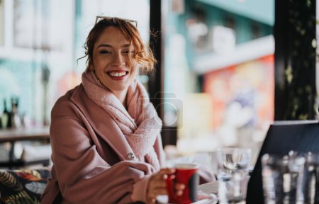 Eleganter Unternehmer entspannt sich bei einer Tasse Kaffee und lächelt im Freien in einem städtischen Café-Ambiente.