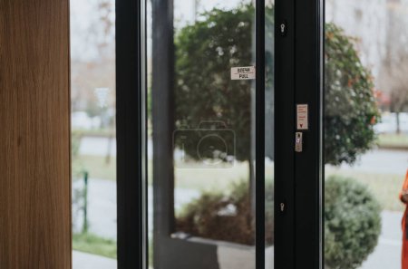 Blick durch eine zeitgenössische Glastür, die mit Pull-Schildern markiert und an einem hellen Tag mit elektronischen Zutrittskontrollsystemen ausgestattet ist.