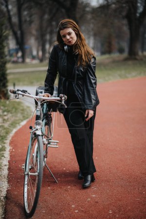 Une femme d'affaires passe du temps avec son vélo dans un parc urbain, mélangeant travail et style de vie en plein air.