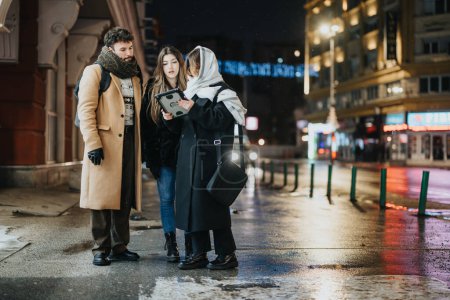 Group of young adults using tablet on urban street at night.