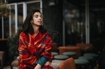 A professional businesswoman enjoys a break outdoors, wrapped in a vibrant plaid blazer, exuding style and confidence.