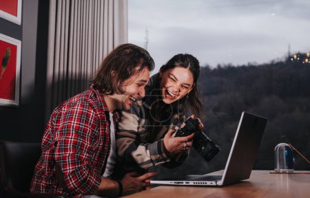 A loving couple sits together at home, engrossed in a photo review session with a laptop and camera.