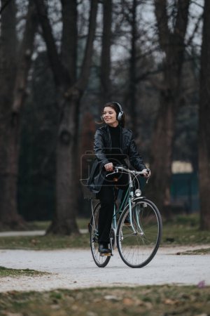 Elegant and confident young woman enjoys a leisurely bike ride through an urban park on her stylish bicycle.
