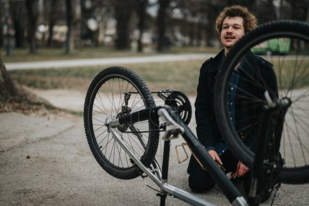 Ein Bild, das einen jungen männlichen Unternehmer zeigt, der sein Fahrrad in einem Park repariert, einer Mischung aus Geschäft und Freizeit.