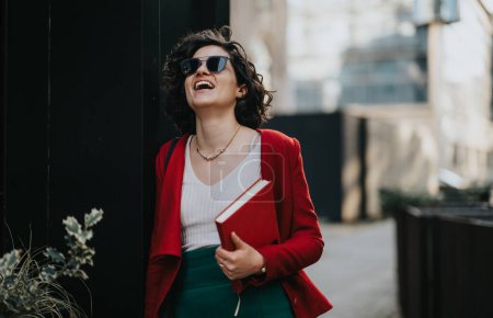 Joyful female entrepreneur in red blazer with notebook enjoying a break outside
