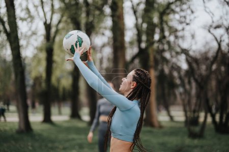 A fit girl with braids enjoys football in a park, showcasing a healthy, active lifestyle and outdoor sports.