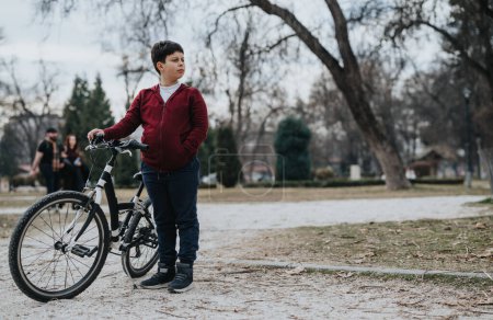 Ein fröhliches kleines Kind gönnt sich eine kurze Pause vom Radfahren, um die Ruhe des Parks zu genießen.