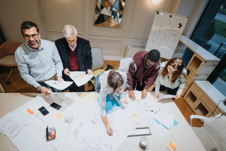 Un equipo dinámico de colegas de negocios multigeneracionales que participan en una reunión colaborativa, una lluvia de ideas y una estrategia juntos en la oficina.