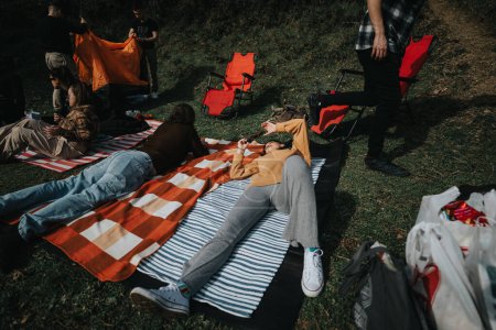 Un groupe d'amis est vu frissonnant et socialisant sur des couvertures de pique-nique dans un parc, avec une atmosphère sereine et contente.