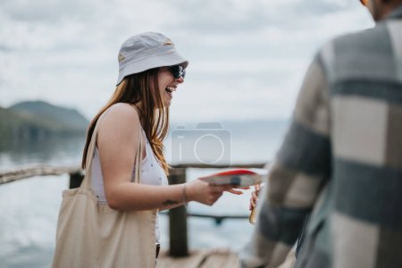 Happy female tourist laughing while chatting with a companion on a lakeside journey during their holiday travel.