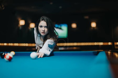 Intense concentration captured as a young woman lines up her shot at a pool table in a moody bar atmosphere.