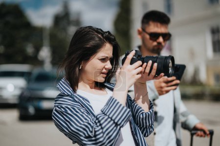 A focused young woman uses a professional camera in an urban setting, guided by a male colleague.