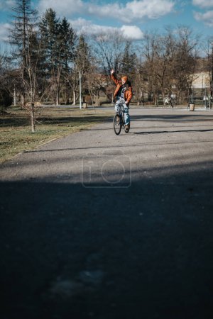 Entspannter junger Mann mit lässigem Stil, der Fahrrad fährt und seine Freizeit in einem sonnigen Park im Freien genießt.