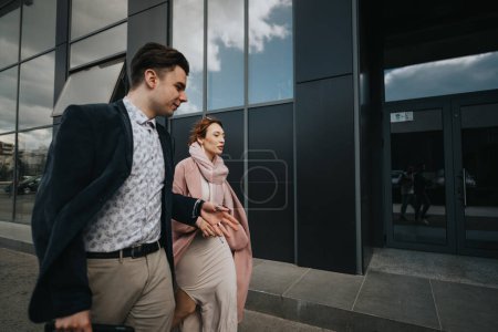 Zwei Geschäftsleute, ein Mann und eine Frau, unterhalten sich bei einem Spaziergang in einem Geschäftsviertel.