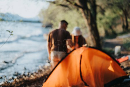 Groupe d'amis se réunissant près d'une tente près d'un lac, profitant du plein air et de l'autre compagnie sur un week-end de loisirs.