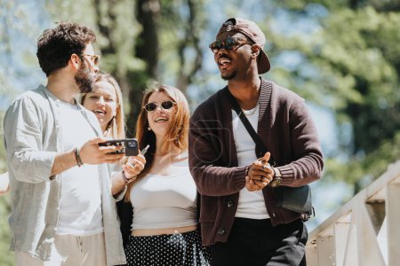 Eine fröhliche Gruppe von Freunden verbringt einen sonnigen Frühlingstag im Freien in einem Park, teilt Lachen und hält Erinnerungen mit einem Smartphone fest.