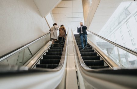 Busy urban professionals ascend on an escalator, with a man focused on his phone call and others in conversation.