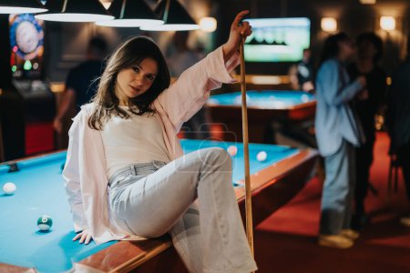 Lässiger, lustiger Abend mit einer stilvollen jungen Frau, die mit Freunden im Hintergrund in einer lebhaften Bar Pool spielt.