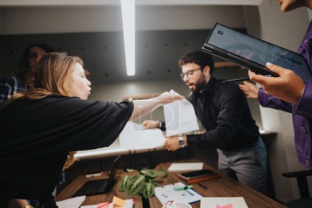 A team of business colleagues engaged in a tense discussion, pointing at documents, showing expressions of conflict and misunderstanding in an office environment.