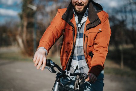 Un homme à la mode en tenue décontractée se détend avec son vélo à l'extérieur, incarnant liberté et loisirs dans un cadre de parc.