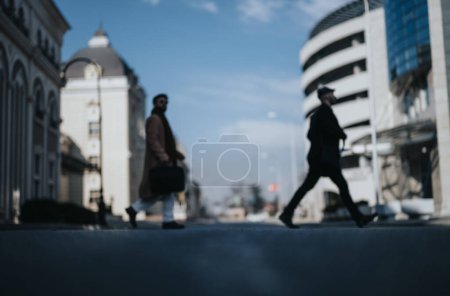 Out of focus shot capturing the hustle of city life with silhouettes of businessmen walking, embodying motion and urban professionalism.