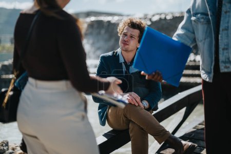 A group of mixed-race business professionals engage in a serious discussion during an outdoor meeting in a city landscape, analyzing documents.
