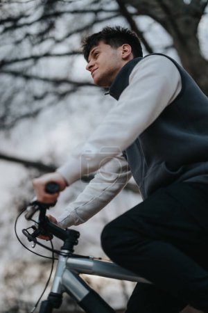 Ein nachdenklicher junger Mann sitzt mit seinem Fahrrad im Park und strahlt ein Gefühl von Freiheit und Freizeit im Freien aus.